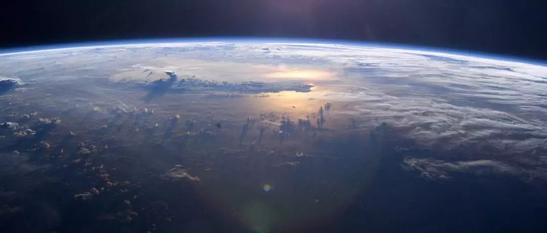 Earth from above showing thunderheads above the ocean reflecting sunlight, photo credit: NASA
