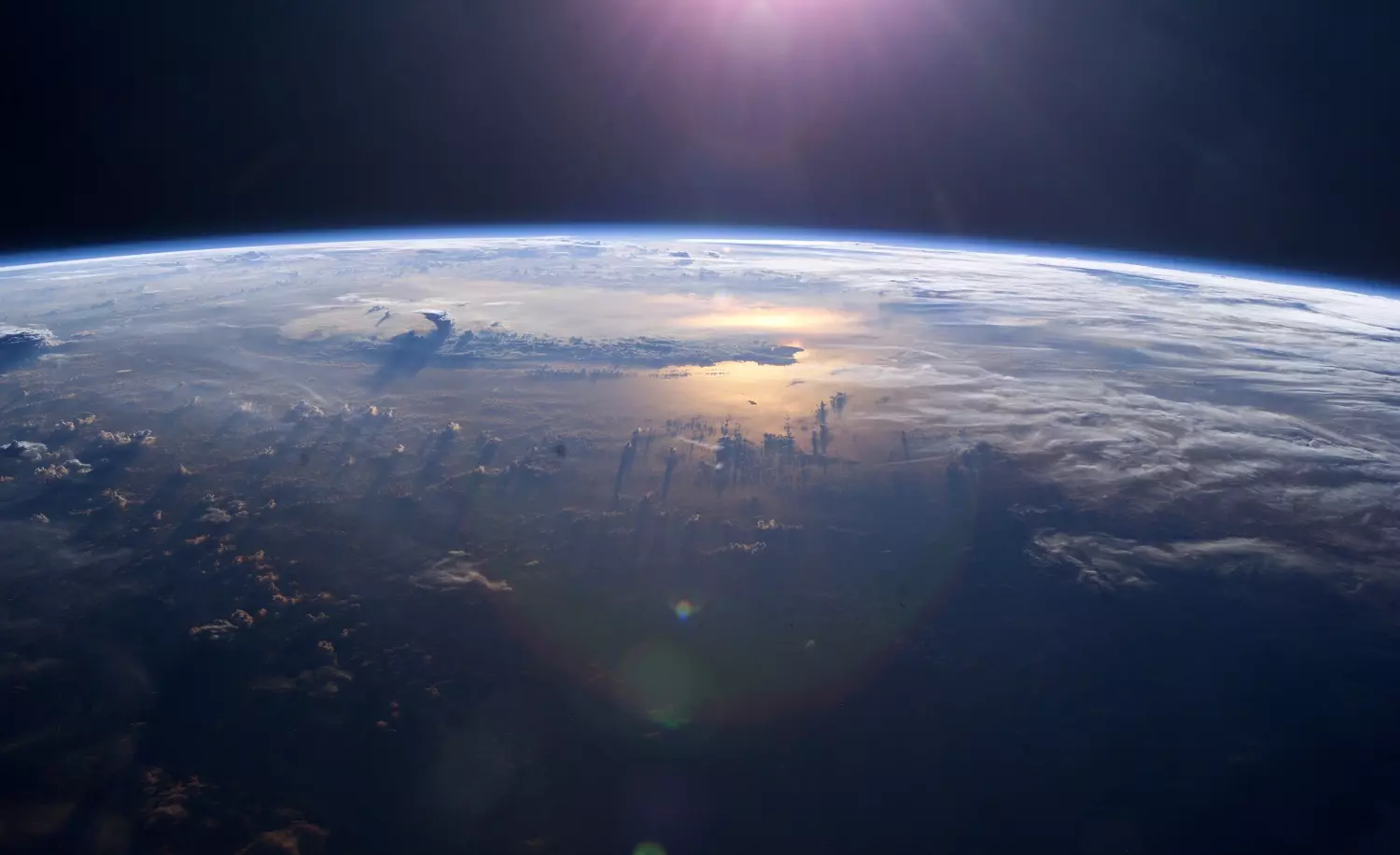Earth from above showing thunderheads above the ocean reflecting sunlight, photo credit: NASA