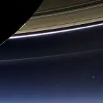 Backlit Saturn with the Earth as a blue dot below