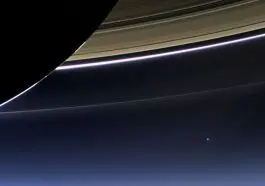 Backlit Saturn with the Earth as a blue dot below