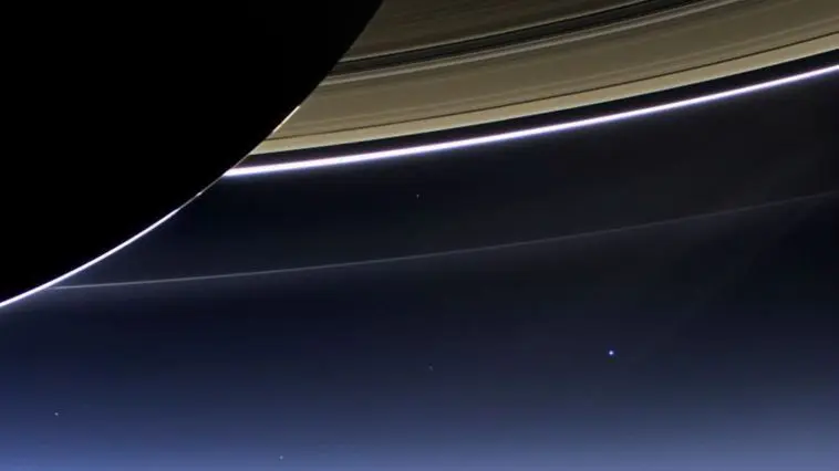 Backlit Saturn with the Earth as a blue dot below