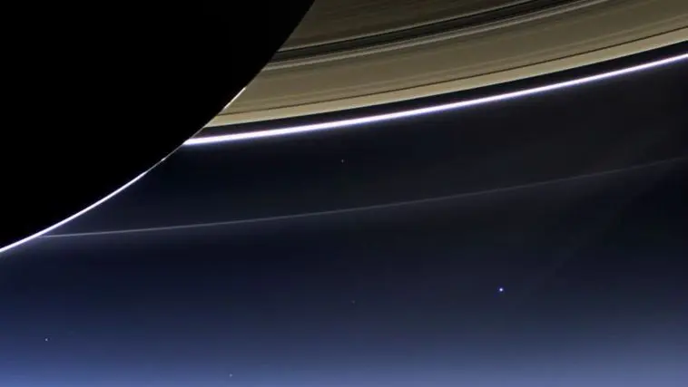 Backlit Saturn with the Earth as a blue dot below
