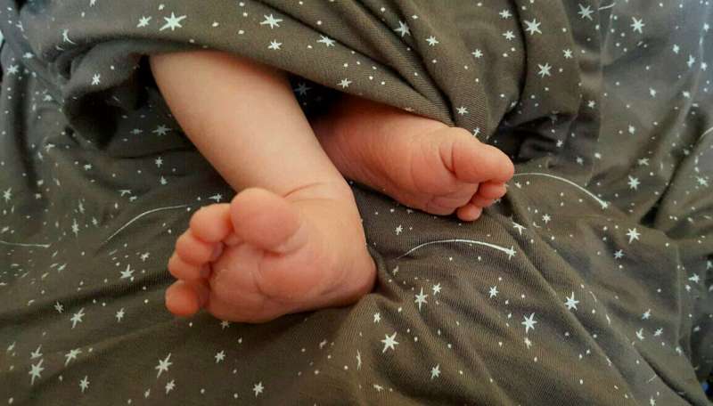 Baby feet on a gray blanket