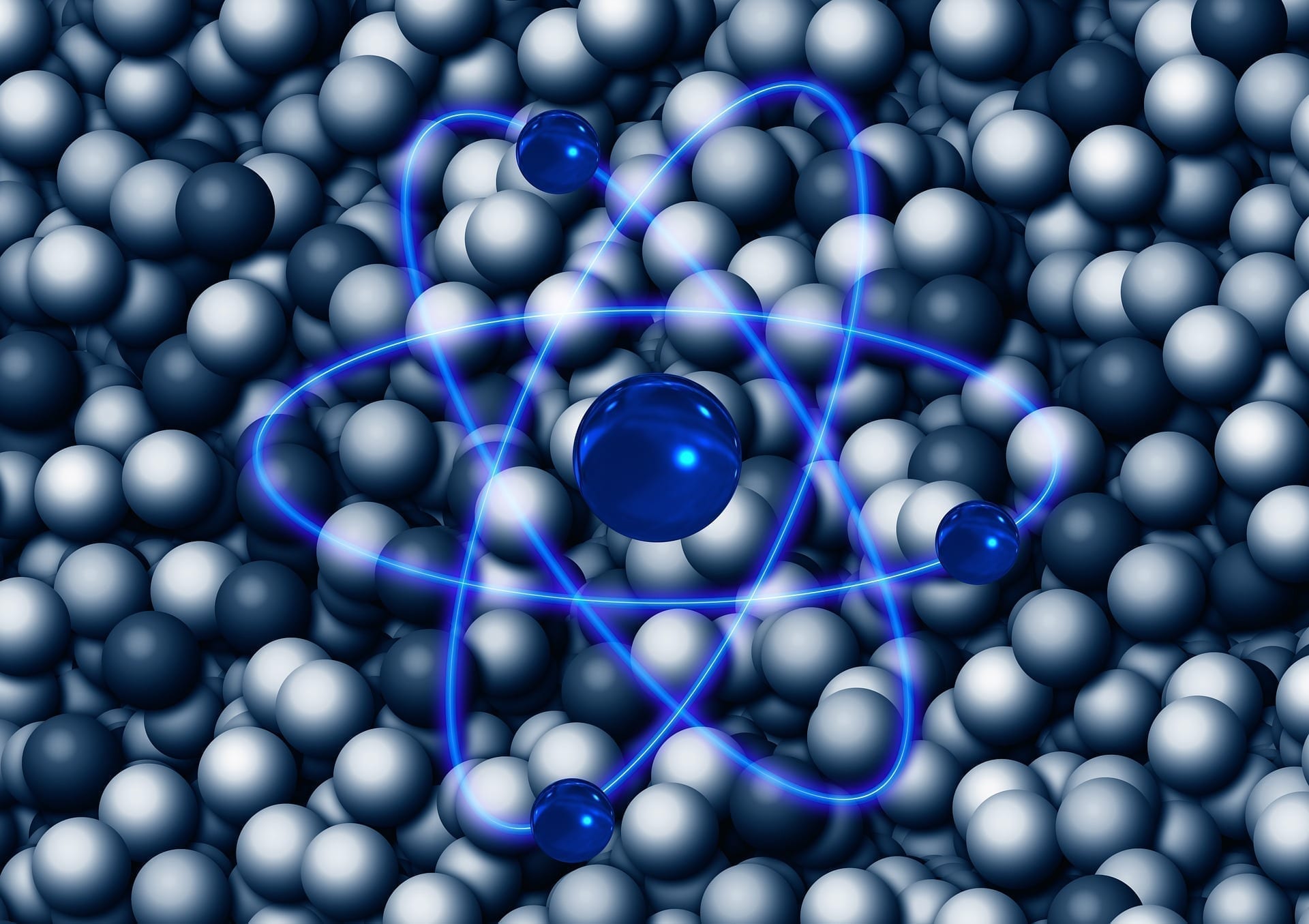 Atom graphic with spherical depictions in the background, photo credit: Pixabay