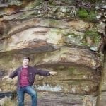David Rives standing between two insitu polystrate tree trunks
