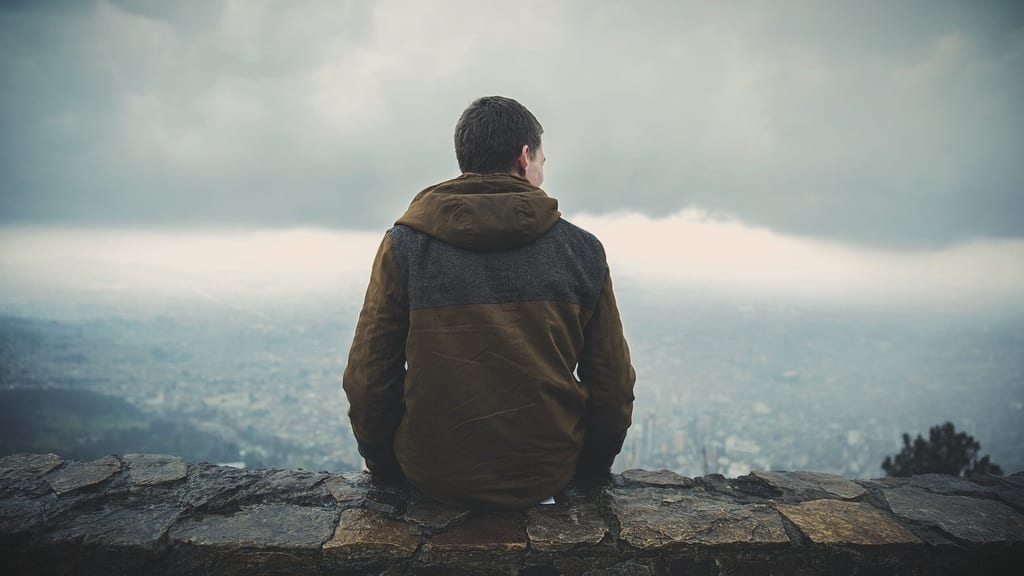 Man sitting on summit overlooking cloudy terrain, photo credit: Pxhere