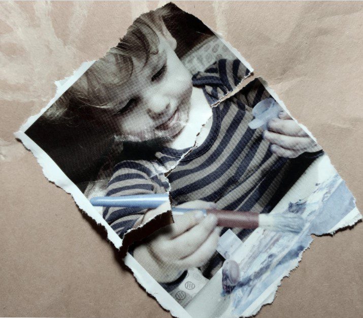 Torn photo of small child painting