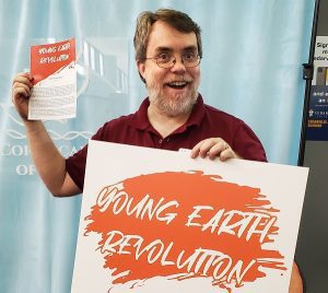 Todd Wood holding Young Earth Revolution material